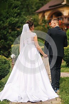 Groom and bride walk in the park on their wedding day. Happy couple spend time together