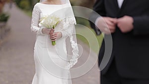 Groom and bride walking in the park by big palace. Handsome man and beautiful woman