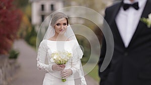 Groom and bride walking in the park by big palace. Handsome man and beautiful woman