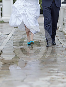 Groom and bride walking in park in rainy day
