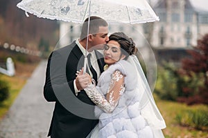 Groom and bride walking in the park on their wedding day. Autumn weather. Rair. Couple umbrella