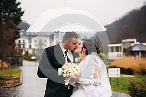 Groom and bride walking in the park on their wedding day. Autumn weather. Rair. Couple umbrella