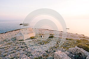 Groom and bride in a white dress stand on the Punta Planka cape near the ancient church against the background of the