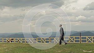 Groom, brunette young man walking on the top of the mountains. Slow motion