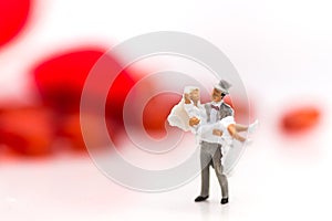 The groom carries the bride in a white wedding dress on a wedding day, with a red heart as a back ground