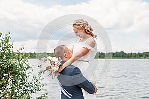 Groom carry bride on hand on nature background lake