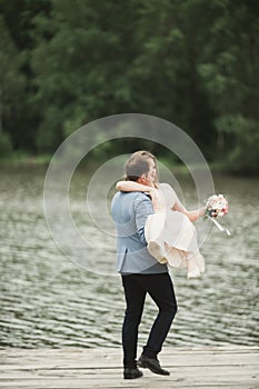 Groom carrying bride near lake and forest