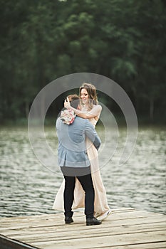 Groom carrying bride near lake and forest