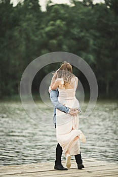 Groom carrying bride near lake and forest