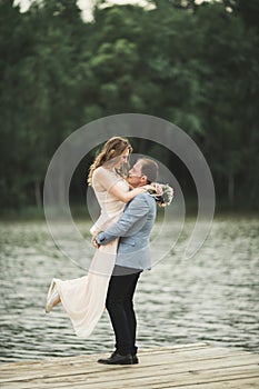 Groom carrying bride near lake and forest