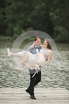 Groom carrying bride near lake and forest