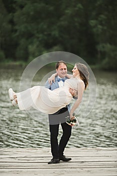 Groom carrying bride near lake and forest