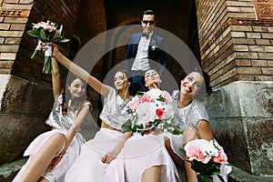 Groom with the charming bridesmaids with the bouquets