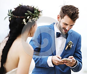 Groom checking his phone at beach wedding ceremony