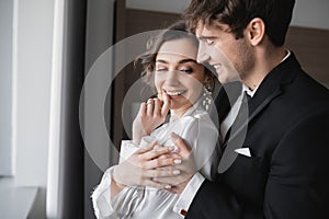 groom in classic black suit embracing