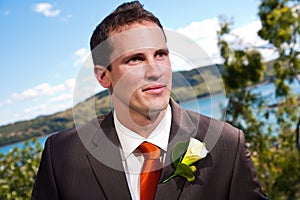 Groom and corsage with blue water behind
