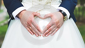 Groom creating heart shape with his hands on the back of the bride.