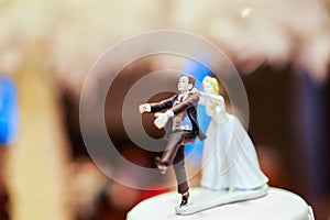 Groom doll and statue is running away but bride can catch him finally. the funny wedding story doll on the top of cake
