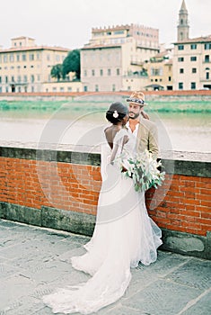 Groom embraces bride on the embankment of the river in Florence. Italy