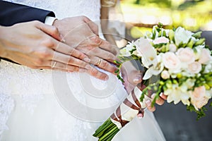 Groom embraces the bride with wedding bouquet. rings on the hands of newly-married couple. bride put her hands on the shoulders of