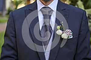 Groom in fancy suit with bouquet waiting for the bride to arrive for wedding ceremony