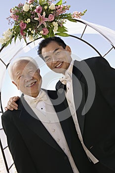 Groom with father under archway outdoors (portrait)