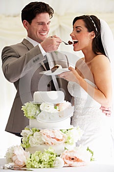 Groom Feeding Bride With Wedding Cake At Reception