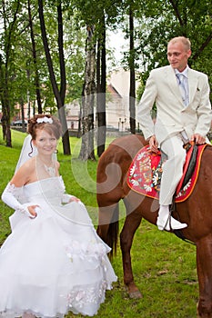 A groom and fiancee sit down on a horse