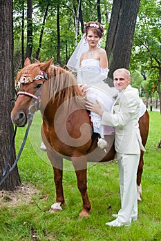 A groom and fiancee sit on a horse