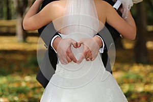 Groom forming heart behind bride