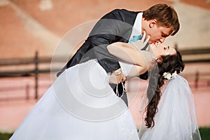 Groom gentle tilted bride, holding her in his arms