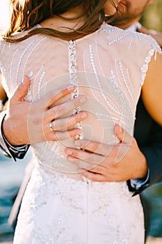 Groom gently hugs the bride in a beautiful white wedding dress