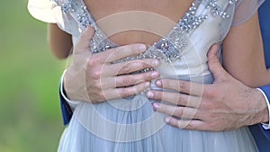 The groom gently hugs the bride, wrapping his arms around her back