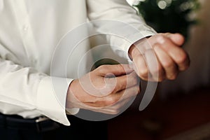 groom getting dressed in the morning, putting on cuff links,wedding preparation