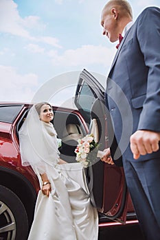 El novio le da la mano a la novia a salir del coche.