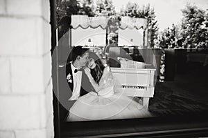 Groom has fun while siitting with a bride at the piano