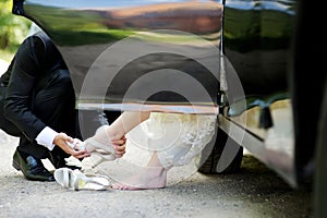 Groom helping bride to put her shoes on