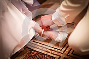 Groom is helping to wear on a bride white shoes