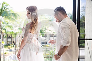 Groom helps the bride to wear a wedding dress