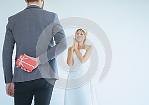 Groom hiding red gift box behind back in order to surprise bride on the wedding day,Woman positive emotion and face astonished hap