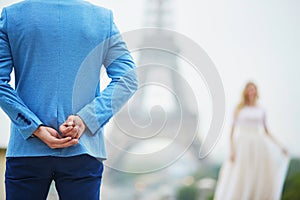 Groom hiding the wedding ring behind his back