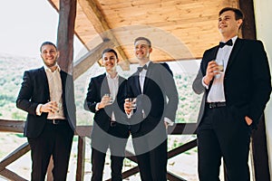 The groom and his friends celebrate the wedding and drink alcohol. Men in suits. Mens emotions and friendship.