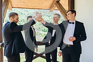 The groom and his friends celebrate the wedding. Men in suits. Mens emotions and friendship.