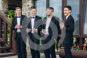 The groom and his friends celebrate the wedding. Men in suits. Mens emotions and friendship.