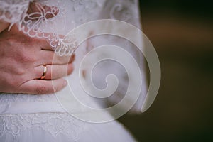 Groom hold bride outdoor. Hand wearing wedding ring on white dress. Close up