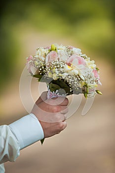 Groom hold wedding bouquet in hand