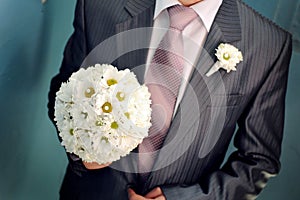 Groom hold wedding bouquet in his hand for bride