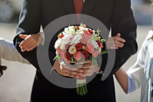 Groom is holding an amazing splendid wedding bouquet of pink re