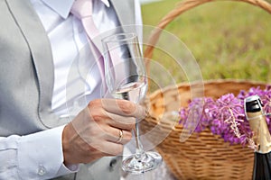 Groom holding a glass with champagne. Groom in suit hold in his hands wine glasses with champagne. Wedding celebration