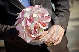 Groom holding his bride`s wedding bouquet